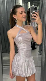 Vestido corto de lurex plateado brillante, con escote halter cruzado, fruncidos en los laterales y falda con volumen tipo globo.