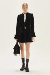 Falda corta de terciopelo negro con diseño ajustado en la cadera y volado en el ruedo.