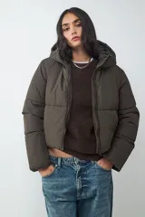 Campera puffer color verde militar, acolchada, con capucha y cierre frontal de cremallera.