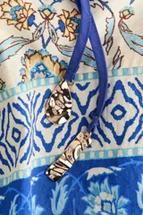 Vestido túnica largo de mezcla de viscosa, con diseño estampado floral en tonos azules y amarillos. Presenta escote en V con frunces, mangas globo con puños elásticos y un cordón fino ajustable en la cintura.