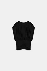 Top negro de punto con cuello redondo y manga corta estilo sisa. Presenta un diseño holgado en la parte superior con delicados frunces y detalle drapeado, y una sección inferior ajustada con frunces verticales y horizontales.