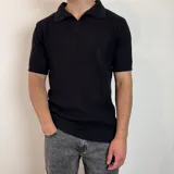 Chomba de tejido de punto en color negro, con cuello polo, cierre frontal parcial y mangas cortas con terminación acanalada.