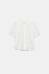 Camiseta blanca de algodón con cuello solapa, manga corta y cierre frontal con botones. Presenta un diseño regular fit con bajo acabado en tejido combinado a tono.