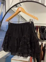 Mini falda negra de encaje con volados en capas y cintura elástica.