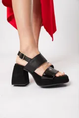 Sandalias negras de cuero con plataforma delantera de 3 cm y taco de 9 cm forrado. Tiene doble tira y ajuste con hebilla.