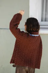 Saco tejido en crochet color marrón, con diseño de textura en relieve, manga larga y cuello grande con bordes en color celeste y crema.