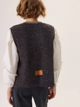 Chaleco de tejido de punto con textura en relieve, color beige, con cierre frontal y bolsillos laterales. Diseño sin mangas con cuello redondo.