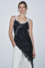 Vestido corto de satén con escote en pico y tirantes finos. Presenta aplicaciones de encaje en el escote y en el bajo, con un diseño asimétrico y abertura lateral.