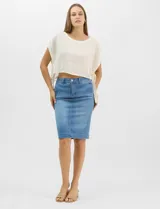 Falda de denim en lavado azul medio con efecto de desgaste localizado, de silueta tubo y largo a la rodilla. Presenta tiro medio-alto, pretina con trabillas, cierre frontal con cremallera y botón metálico, bolsillos frontales y costuras verticales que estructuran la prenda.