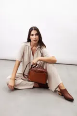 Zueco slingback negro de cuero vacuno con textura grabada geométrica, taco bloque de madera y tira ajustable con hebilla metálica.