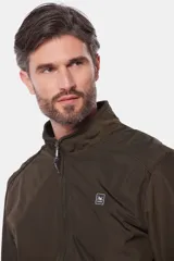 Campera liviana de color verde grisáceo, con cierre frontal, cuello alto y puños elásticos. Presenta un pequeño parche con logo en el pecho.