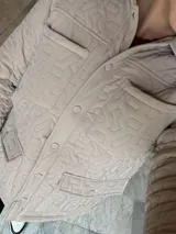 Campera verde militar acolchada con cuello camisero, cierre frontal con botones a presión, bolsillos de parche con solapa en el pecho y bolsillos laterales.