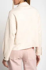Camisa tipo sobrecamisa oversize color crudo, confeccionada en tejido de gamuza vegana con cierre frontal de botones metálicos y cuello clásico.