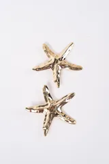 Par de aros con diseño de estrella de mar en acabado metálico dorado con textura irregular.