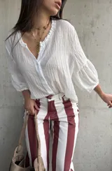 Camisa blanca de tejido liviano y fresco, con calce suelto, cuello de inspiración romántica y mangas amplias con frunces.