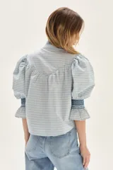 Blusa de algodón a cuadros en tonos celestes y beige, con mangas abullonadas, cuello alto y detalles de punto smock en cuello y puños.