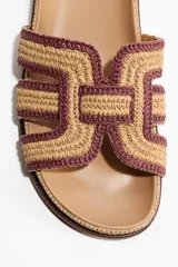 Sandalias H&M tipo chinela con plantilla preformada color tostado y tira ancha en el empeine confeccionada en paja trenzada con diseño geométrico en tonos beige y bordó.