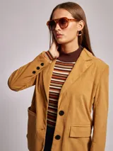 Blazer color ocre de pana con cuello y solapa, manga larga, bolsillos delanteros con solapa y cierre frontal con dos botones.