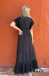 Vestido largo negro con escote en V, mangas cortas con volados, corte imperio con lazo ajustable y falda escalonada con detalles bordados.