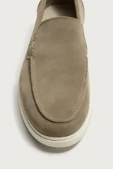 Mocasines casuales para hombre, fabricados en piel con acabado en serraje color marrón, de corte liso con detalle de bordón y suela blanca a contraste.
