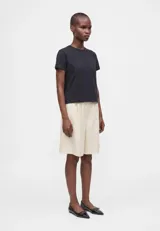 Remera blanca de algodón con corte boxy, ligeramente oversize, de líneas rectas y mangas cortas, con cuello redondo acanalado.
