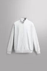 Sudadera de corte relajado con cierre frontal de cremallera, confeccionada en tejido ligero de mezcla de algodón. Presenta cuello subido, manga larga, bolsillos laterales ocultos en costura y acabados en rib.