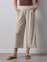 Pantalón capri plisado color beige, marca Dictionary, con pretina ancha elastizada y bolsillos delanteros.