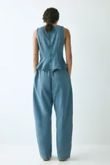 Pantalón oversized en denim de algodón rígido, con elástico revestido en la cintura, cierre con botón y bolsillos laterales discretos. Presenta un corte con piernas de diseño curvo y volumen.