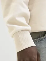 Buzo color crema de algodón con cuello redondo, manga larga y puños acanalados. Estampa en la espalda con la palabra "POISONOUS" y un diseño floral.