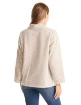 Buzo de tejido soft mohair con estampado zigzag en tonos beige y blanco. Presenta cuello polo, escote en V con botones a presión y manga larga amplia. El bajo tiene tajos laterales y apliques metálicos.