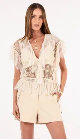 Blusa de encaje de mujer con transparencias, escote en V y mangas cortas con volados, confeccionada con motivos calados y cintura definida.
