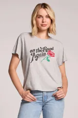 Remera gris melange de corte holgado, manga corta y cuello redondo, con estampa frontal que incluye la frase 'On the Road Again', el nombre 'Willie Nelson' y una rosa roja con tallo verde.