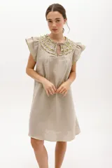 Vestido negro de lino, corte suelto, con cuello redondo con volados y mangas cortas con volados.