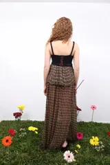 Top sin mangas con breteles finos, que combina un cuerpo superior tejido en crochet negro con una sección inferior de tejido plano artesanal en tonos tierra con detalles en amarillo y rojo.