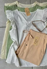 Blusa beige de manga corta con cuello redondo y bordado en el ruedo.