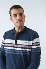 Remera tipo polo de manga larga azul marino con rayas horizontales blancas, grises y rosadas en el pecho. Tiene cuello clásico con botones y logo estampado en el pecho. Corte regular.