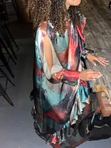 Vestido largo de poliéster con estampado abstracto en tonos rojo, azul y negro. Presenta mangas largas y volados en el ruedo.