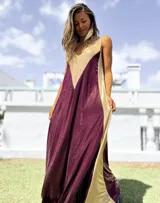 Vestido largo de corte holgado con diseño bicolor en tonos bordó y dorado, confeccionado en tela satinada con acabado brillante. Presenta escote en V y breteles anchos.