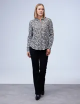 Camisa estampada blanca y negra con cuello clásico, abertura frontal con botones ocultos y mangas largas con puños abotonados.