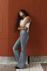 Jeans de tiro alto, color gris oscuro lavado, con corte ajustado en la parte superior y pierna acampanada (flare) desde la rodilla hasta el bajo. Presenta cinco bolsillos y cierre frontal con botón.