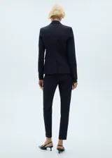 Pantalón de traje tiro medio, color azul marino, de diseño recto con trabillas, cierre oculto de botón, gancho y cremallera, dos bolsillos laterales y dos bolsillos de ribete en la parte posterior.
