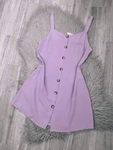 Vestido corto lila con breteles finos y botones frontales.