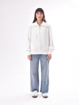 Buzo negro de punto con cuello polo con cierre de cremallera metálica, mangas largas abullonadas y bolsillos laterales.