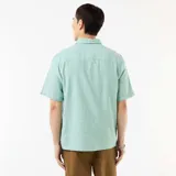 Camisa de manga corta en mezcla de lino color verde menta, con cuello camisero, cierre frontal de botones y diseño holgado.