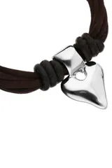 Pulsera compuesta por múltiples cordones trenzados de efecto seda y cuero en tono marrón oscuro, con un dije central metálico plateado con forma de corazón estilizado. Cuenta con cierres y argollas de metal plateado.