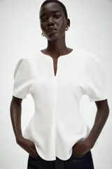 Camiseta negra de cuello redondo con escote en pico, manga corta abullonada y bajo con diseño peplum.