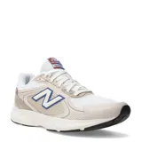 Championes urbanos New Balance modelo Amaste, con diseño en tonos beige y blanco, detalles en azul y rojo en la lengüeta, y el logo característico en el lateral.