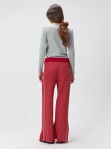 Pantalón de punto jacquard con diseño geométrico texturizado, de corte holgado y pierna ancha. Presenta tiro medio, cintura elástica con cordón ajustable y aberturas laterales en el ruedo.