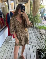 Vestido corto de color verde militar con estampado floral, escote en V con ribete contrastante, mangas tres cuartos abullonadas con puños elastizados y diseño holgado.