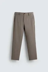 Pantalón chino de corte slim fit, confeccionado en tejido elástico. Presenta bolsillos frontales, bolsillos traseros de vivo con botón y cierre frontal con cremallera y botón.